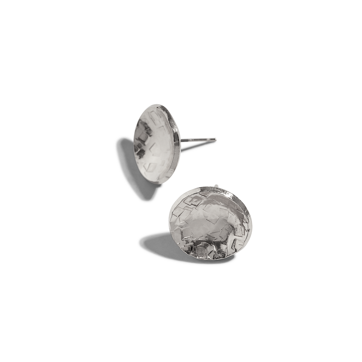 The Buttercup Textured Stud Post Earrings by JAREDJAMIN Jewelry Online, crafted in 18K gold-plated brass with a hammered geometric pattern, are displayed on a white background—one earring flat, the other propped up with soft shadows.