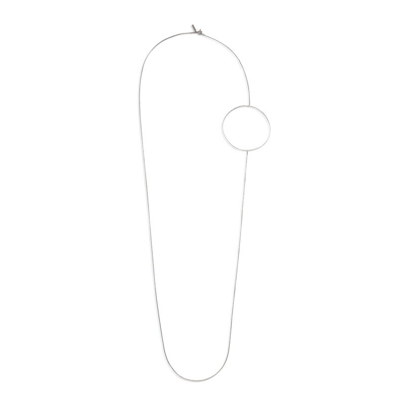 JAREDJAMIN ジュエリーオンライン シルバー Halo ネックレス 特徴とする a long, thin シルバー-tone チェーン 付きの large circular ペンダント on one sideとa toggle clasp, creating an asymmetrical ミニマリスト look against a plain 白い背景.