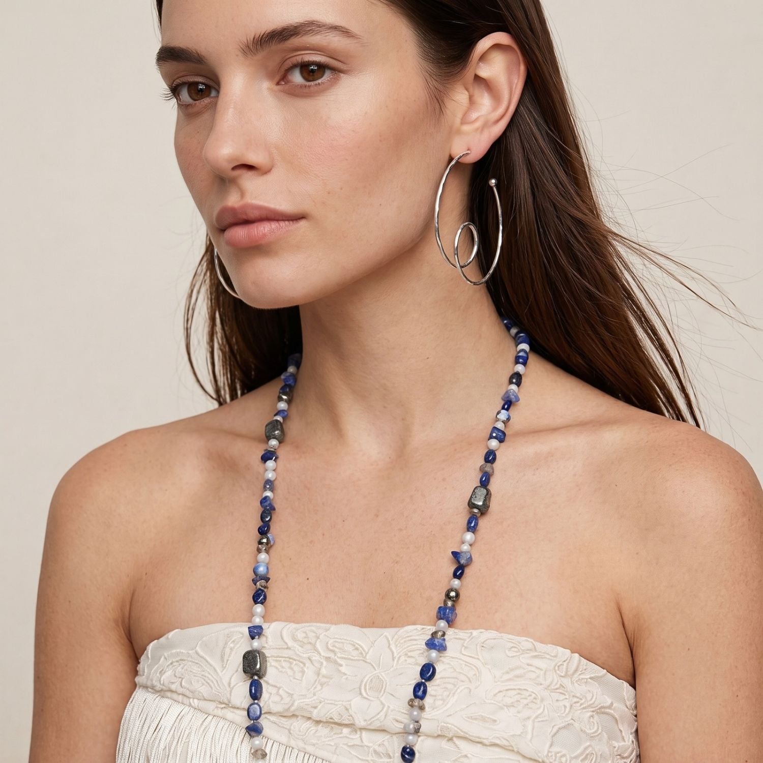 The Silver Loop-De-Loop Hoop Post Earrings by JAREDJAMIN Jewelry Online are silver-plated brass hoops with a hammered texture and spiral loop detail, shown overlapping on a white background in a modern, artistic style.