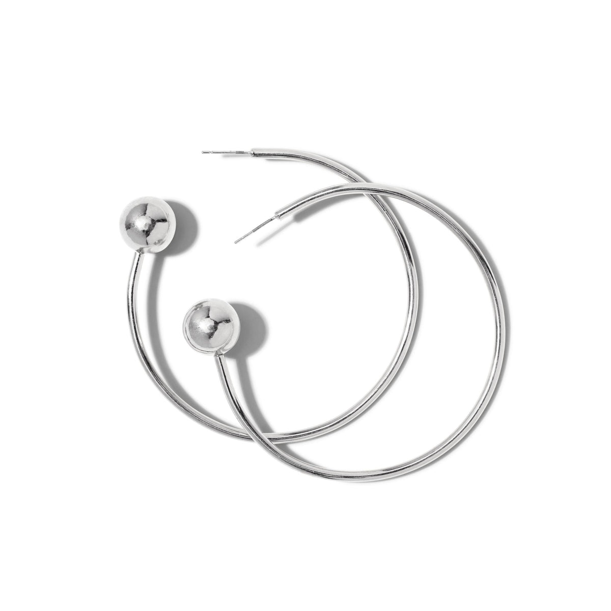 Les argent Orbita Comet boucles d'oreilles par JAREDJAMIN Bijoux en Ligne présentent two large, argent rhodium créoles avec a smooth, brillant bead near the post. Their 3" pendante offers a modern, minimalist style, shown overlapping sur un fond blanc.