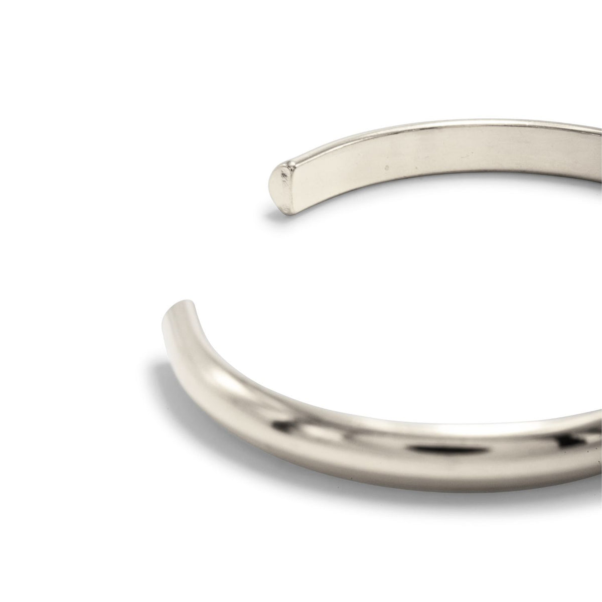 A close-up captures the Silver Parker Cuff—sculpted and hand-assembled in our West Hollywood studio. This polished, open-ended silver form punctuates a white backdrop. Crafted in small batches with eco-conscious precision. Style note: transitions from denim to tuxedo.