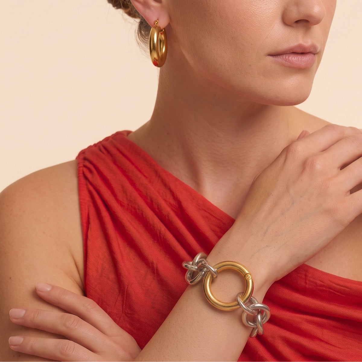 Portrait of a model wearing a red top and the Silver Parker Link Chain Bracelet featuring the contrasting gold clicker clasp, demonstrating the mixed-metal styling on the wrist.