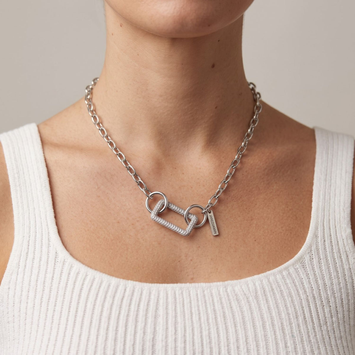 Front view portrait of a model wearing the high-polish silver pavé rectangular clicker clasp styled as a focal connector on a silver link chain necklace.