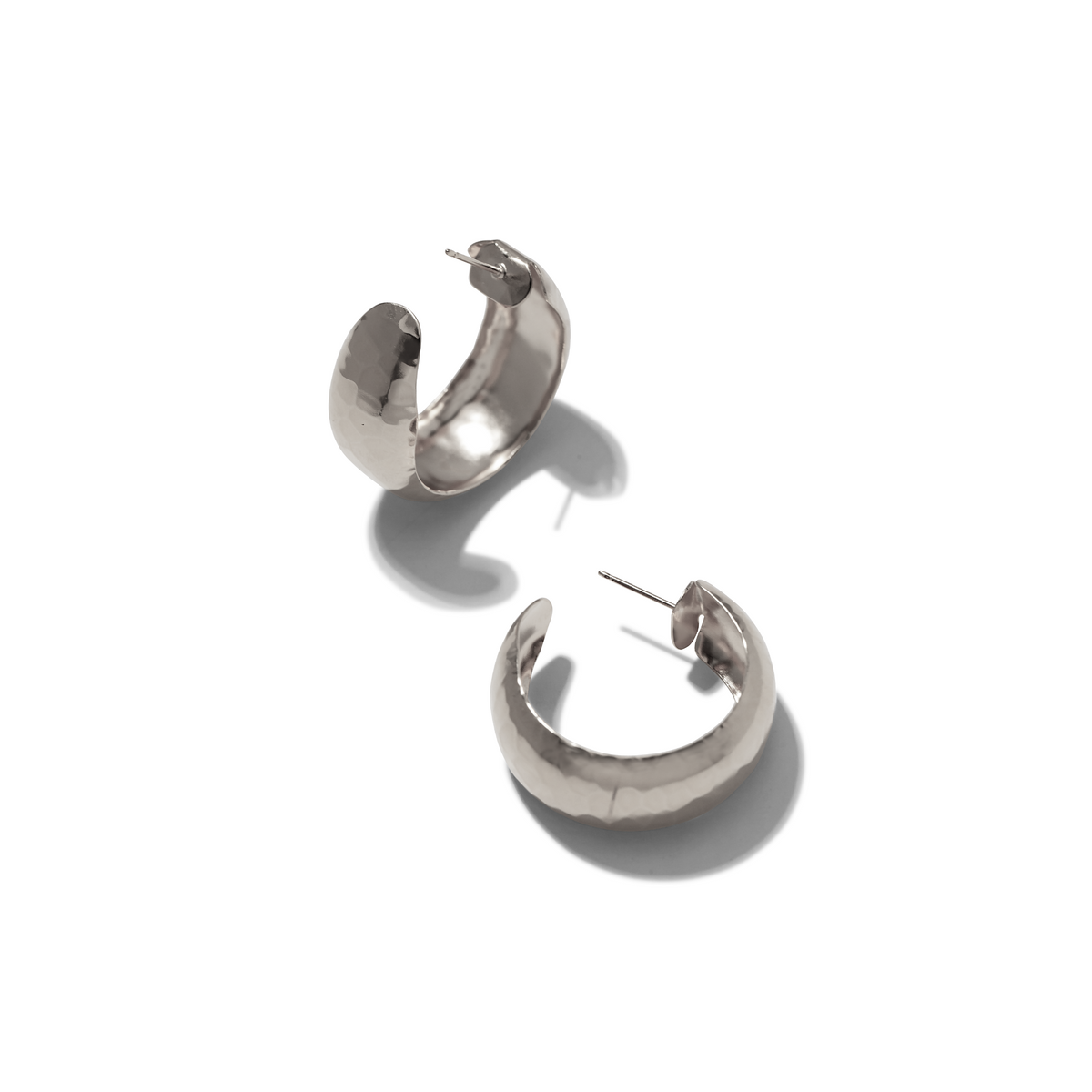Les argent Rush créole boucles d'oreilles par JAREDJAMIN Bijoux en Ligne présentent chunky, hammered argent plate créoles for pierced ears. Their reflective artisan finish creates a weightless look avec soft shadows highlighting each detail.