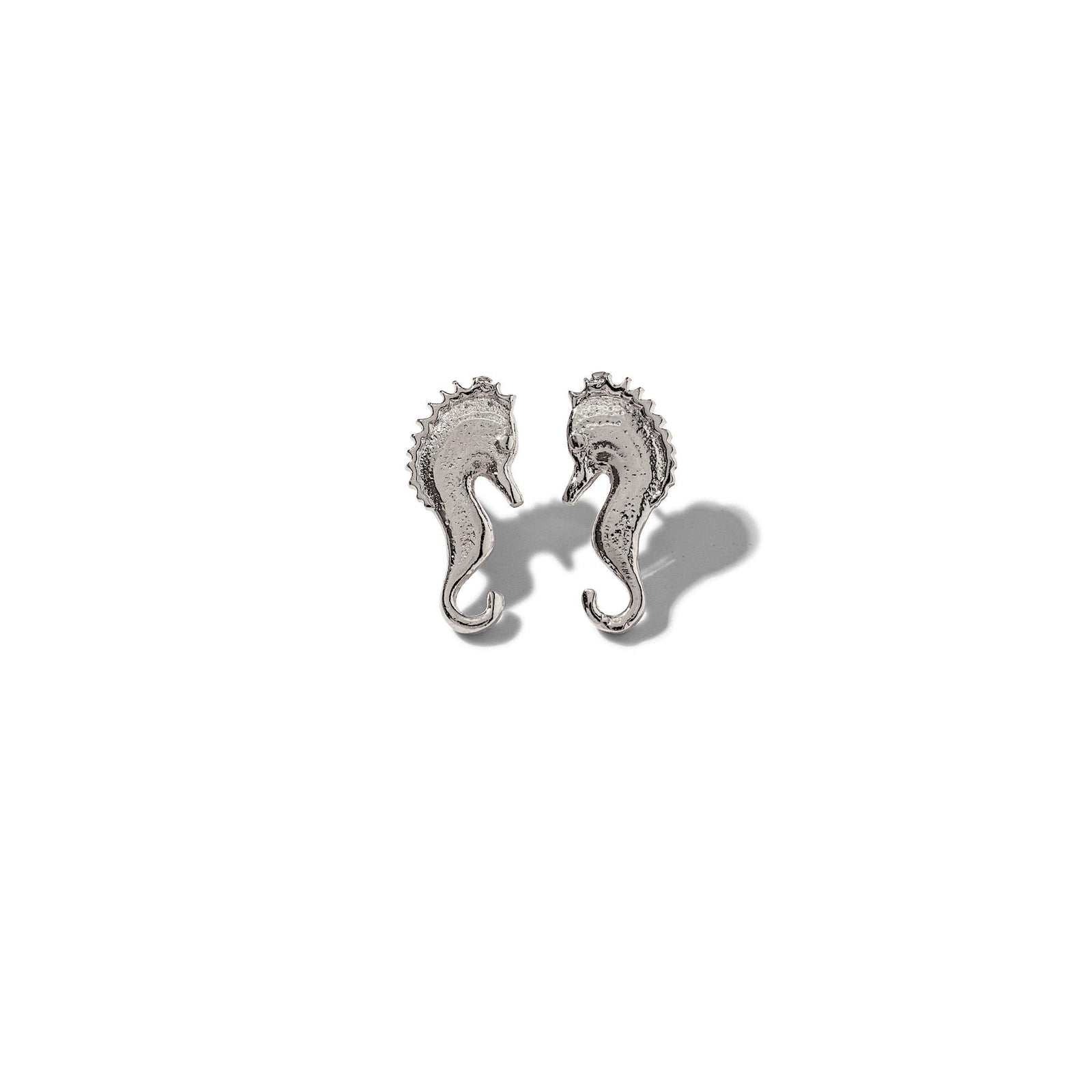The Sea Scooter Post Earrings by JAREDJAMIN Jewelry Online are small, silver-plated seahorse studs with detailed, textured bodies and curled tails, shown facing each other on a plain white background.