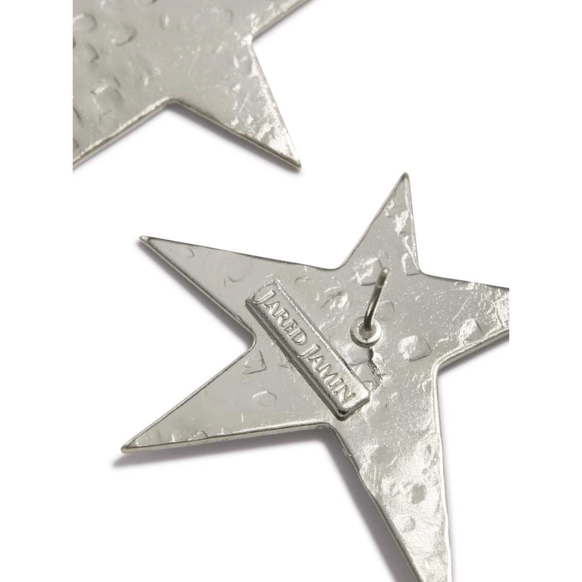 primer plano of two texturizado plata-tone star-shaped pendientes. Los focused plata Shooting Star pendiente de botón de JAREDJAMIN Joyería Online features a raised "JARED JAMIN" plaque y loop, perfect for fans inspirado en STAR WARS PREMIERE style.
