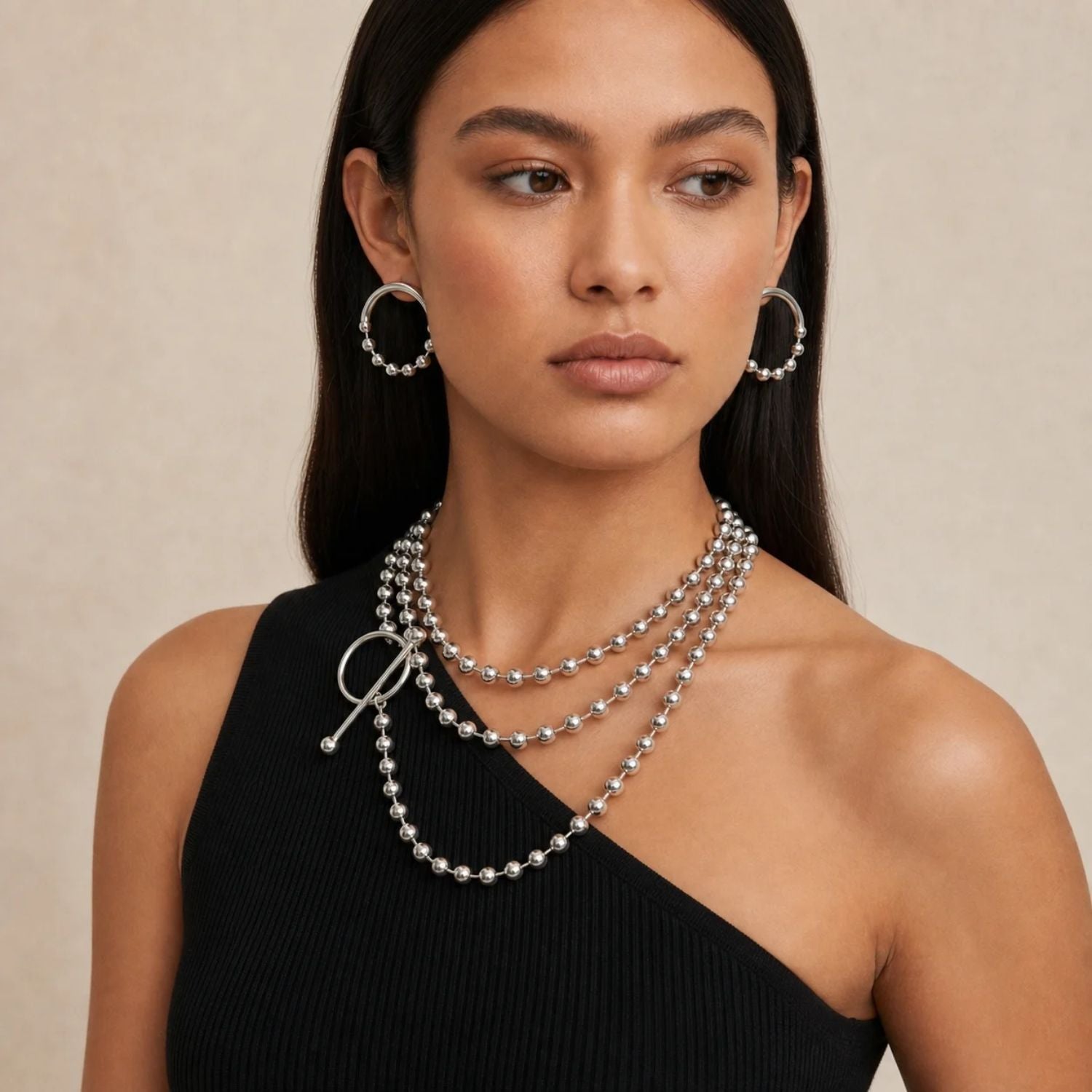 Pair of silver open-circle post earrings on white, each with a thick polished upper arc and a lower arc of small silver spheres.