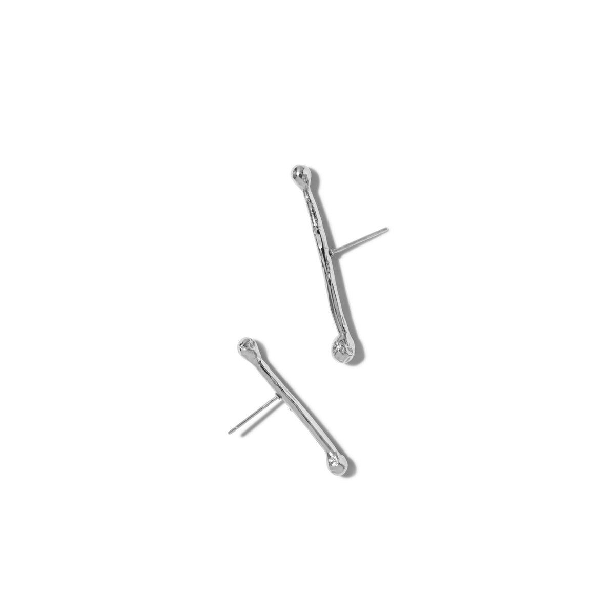Los plata Stix Post pendientes de JAREDJAMIN Joyería Online presentan a minimalist, twig-inspired design con a curved silhouette y platinum-to-plata plating. Each pendiente de botón has a straight post y is exhibido sobre a plain fondo blanco.