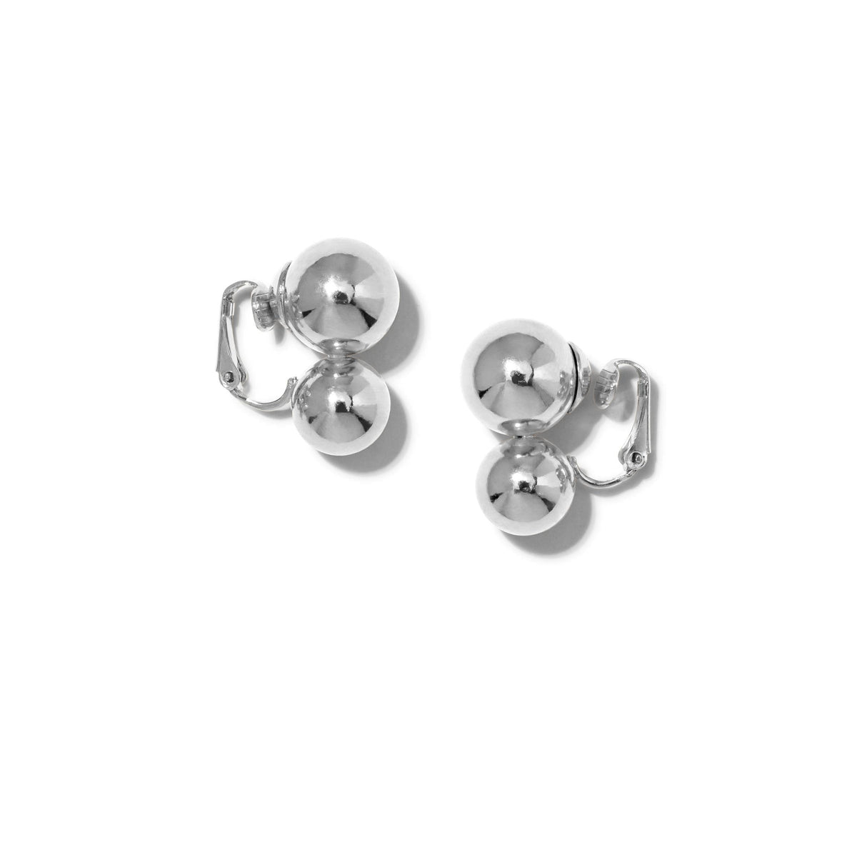 Los plata Uptown Orbita Clip On pendientes de JAREDJAMIN Joyería Online presentan two smooth, reflective plata spheres stacked vertically con a hinged clasp, offering vintage flair. exhibido sobre a plain fondo blanco.