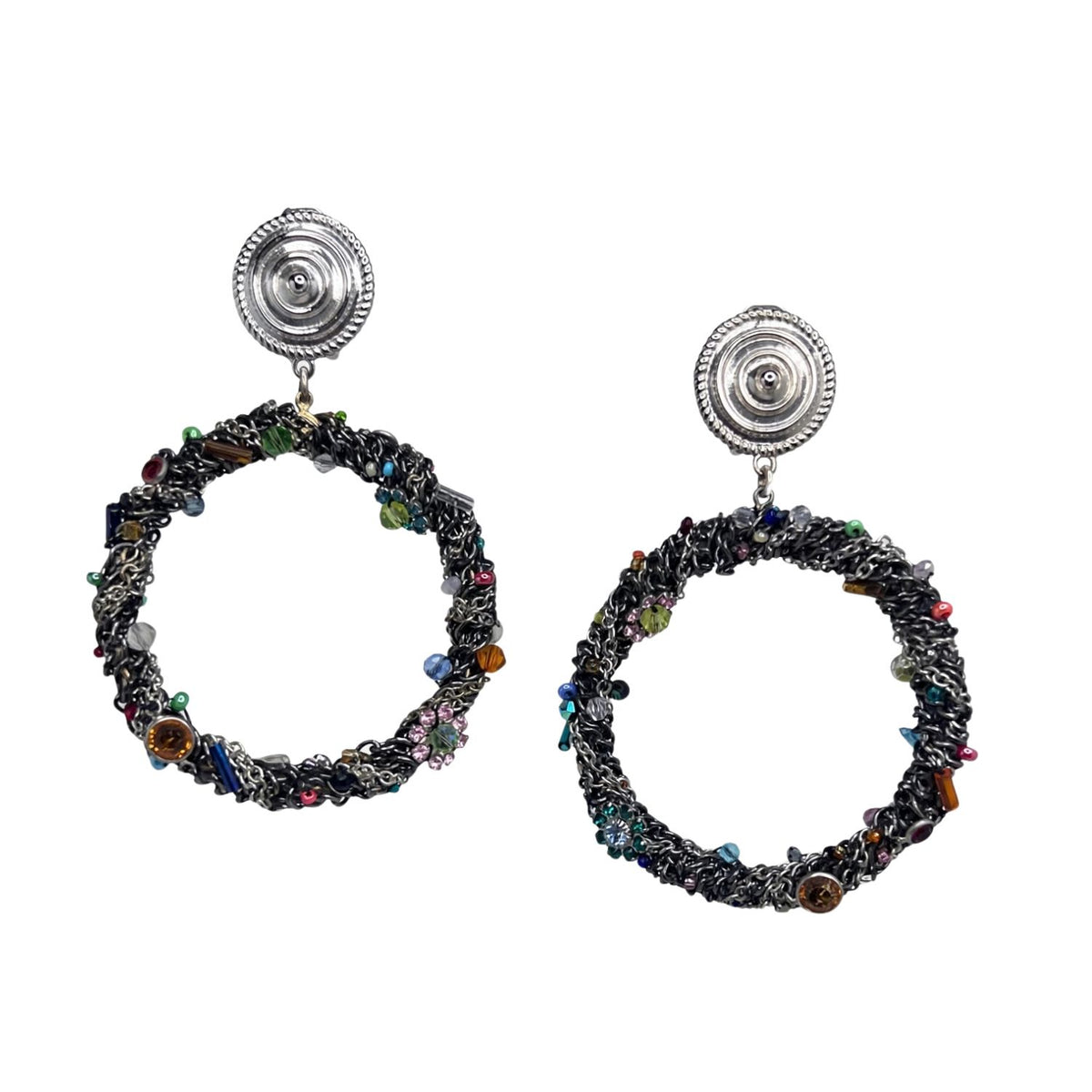 Simone Clip On Earrings by JAREDJAMIN — the full pair photographed flat on a white background: silver-tone embossed disc clip tops with rope-twist edges above dark crocheted wire hoops densely set with multicolor Swarovski crystals, rhinestones, glass beads and ornamental charms