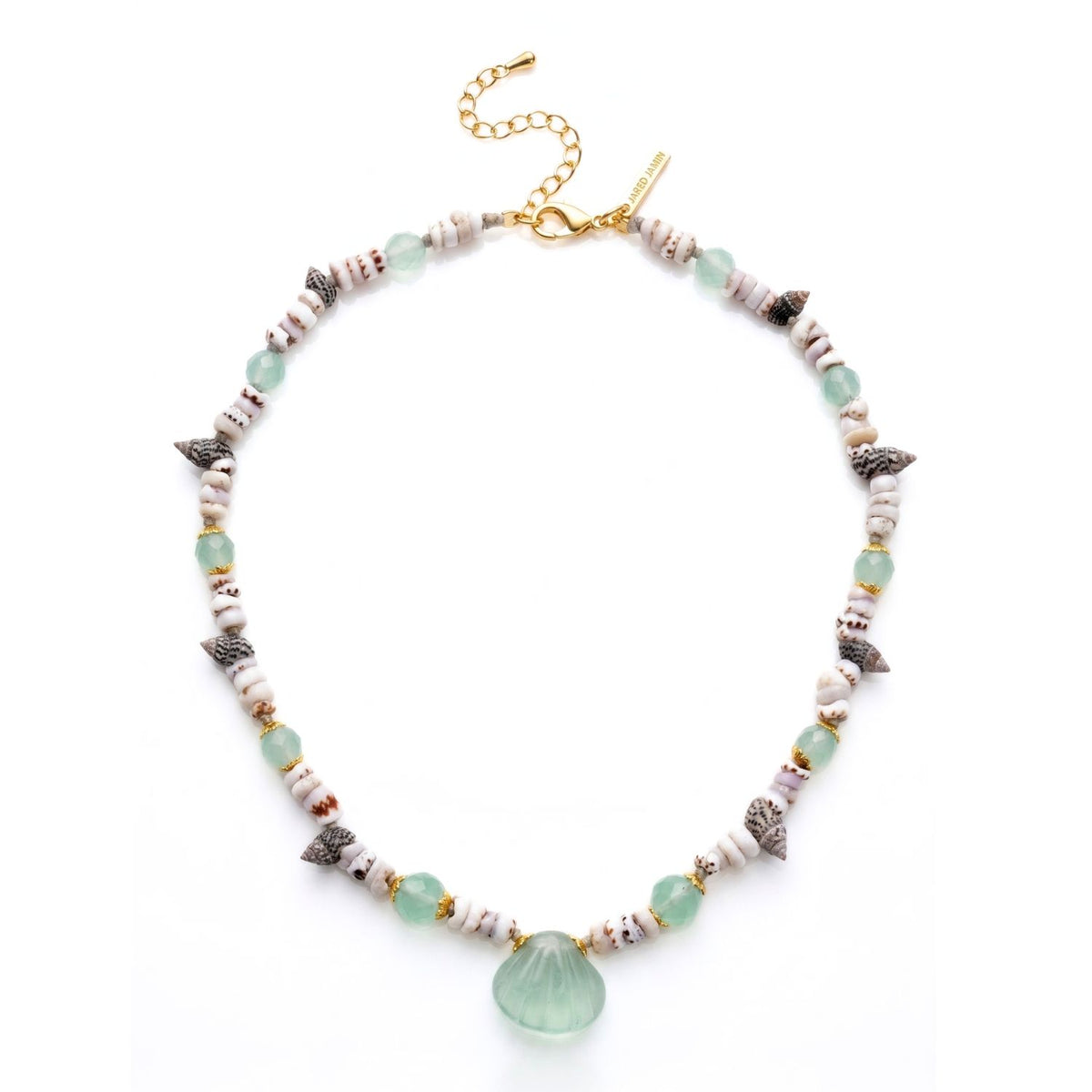 Studio product shot of the JAREDJAMIN Sirena one-of-a-kind necklace on a white reflective surface, highlighting the central hand-carved green aventurine shell pendant, faceted aventurine beads with gold caps, segmented upcycled shell discs, grey sea shells, and the gold-plated lobster clasp extension.
