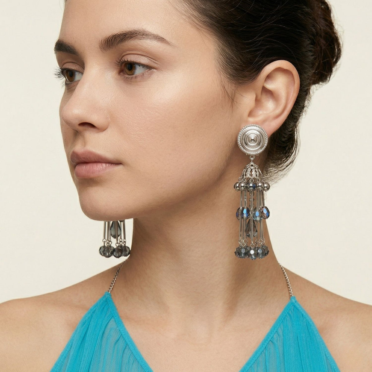 A woman with a sculpted updo in sheer turquoise lets the Sixties Solar Sister Clip On Earrings refract quietly at her profile—hand-assembled in our West Hollywood studio. Small-batch, eco-conscious. Style Note: punctuates denim and after-dark silk alike.
