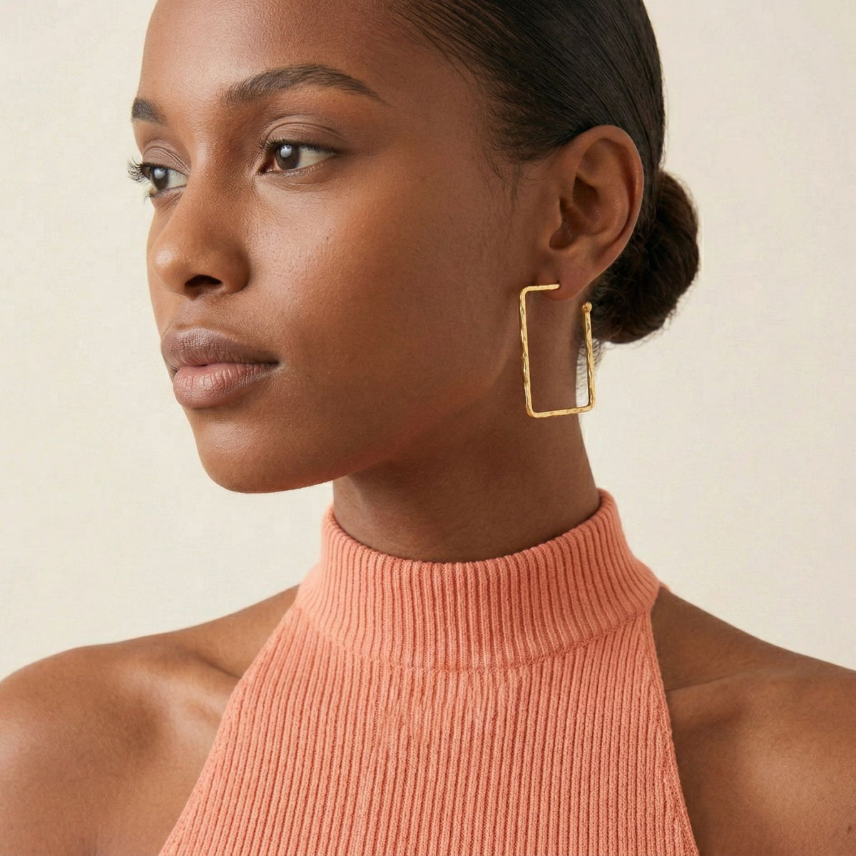 or Squaretastic créole Post boucles d'oreilles avec scratch-resistant E-coating de JAREDJAMIN Bijoux en Ligne are worn by a woman avec a neat low bun, styled avec a ribbed sleeveless peach top, set against a light neutral background.