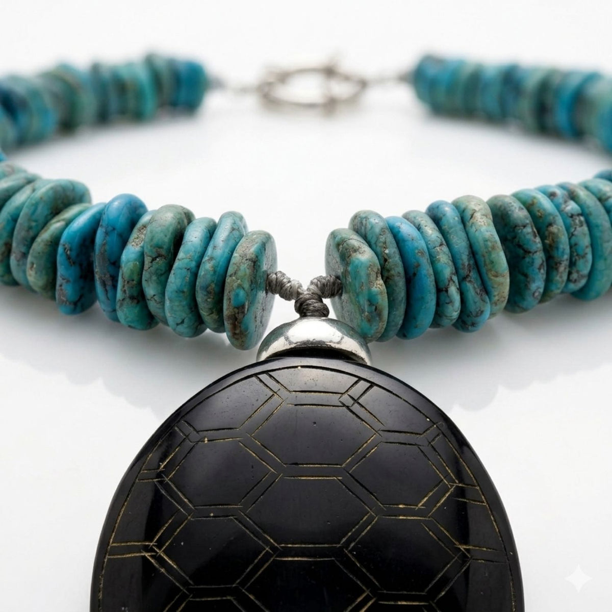 Close-up studio shot focusing on the silver-plated bead cap and geometric lattice engraving on the 2x2.5-inch dark brown jade pendant, suspended from hand-knotted turquoise howlite disc beads.