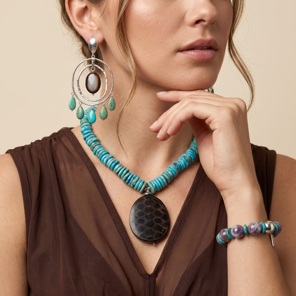 Front view portrait of a model wearing the 17-inch Solana turquoise and carved jade collar necklace paired with a brown top, styled alongside matching collection pieces.