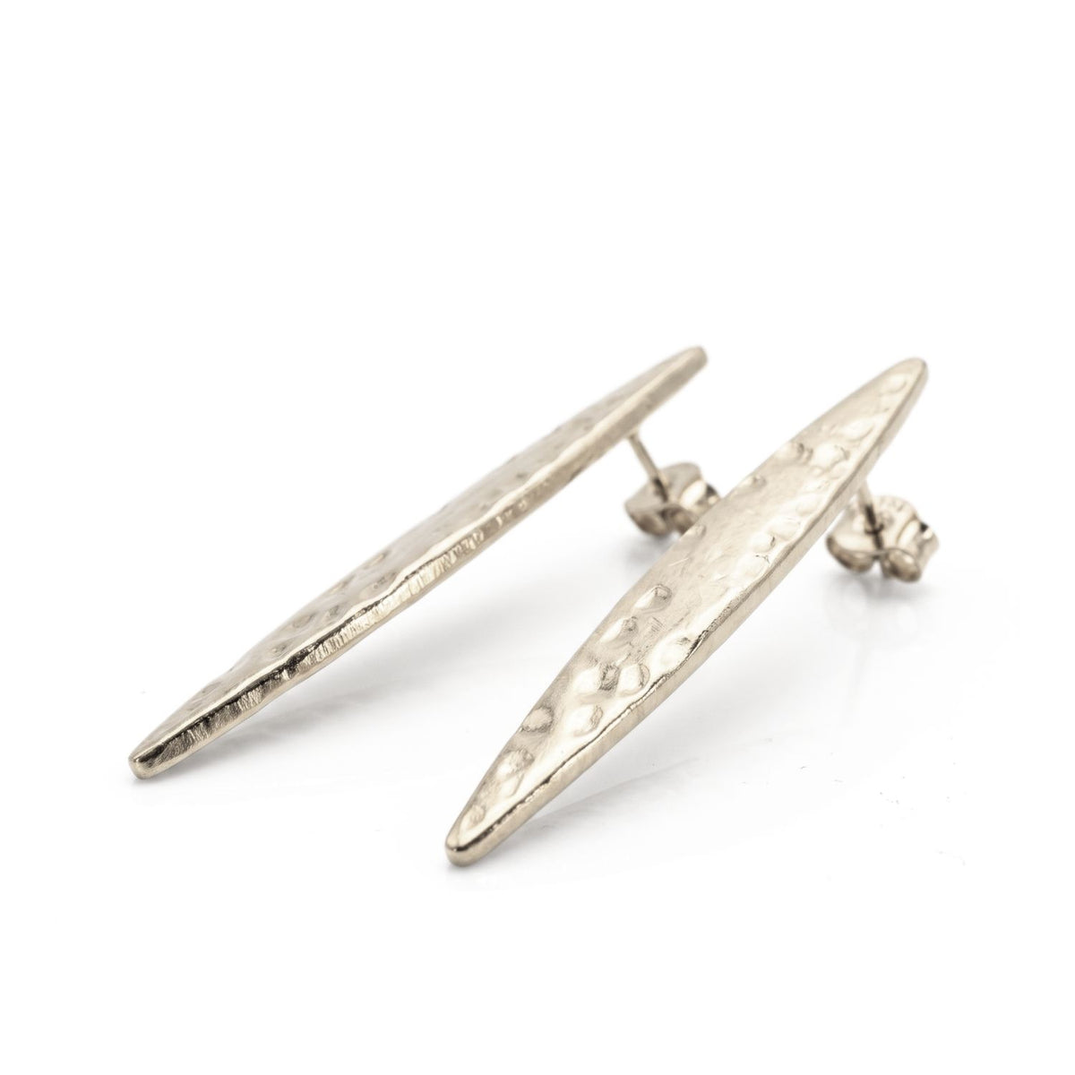 Studio product shot showing the pair of silver-plated Soren Hammered Marquise Post Earrings resting at an angle on a white background, displaying their post backings and hand-hammered texture.