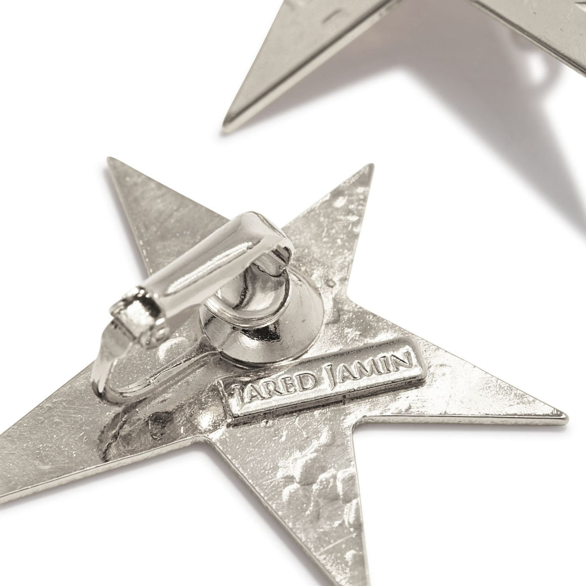 A close-up of Silver Shooting Star Dangle Clip On Earrings: each star is hand-assembled in our West Hollywood studio, sculpted from tarnish-proof silver in small, eco-conscious batches. Style note: refracts edge from crisp shirts to after-dark velvet.