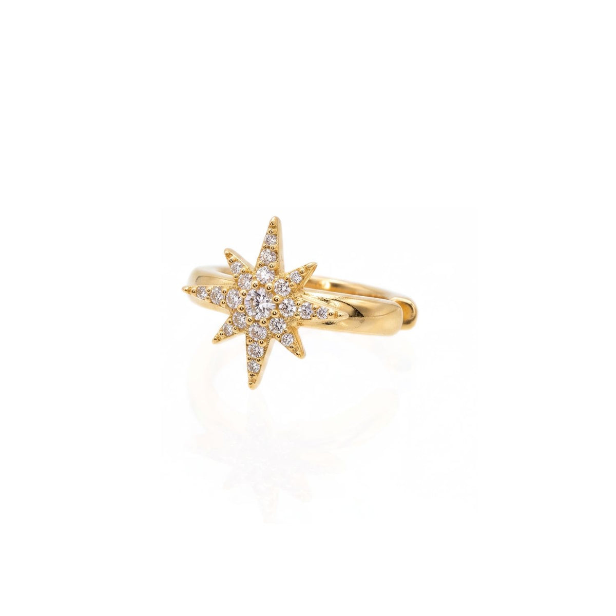 Angled studio shot of the Astra gold ear cuff resting on a reflective white surface, detailing the hollow cuff gap and the precise micro-pavé settings of the starburst.