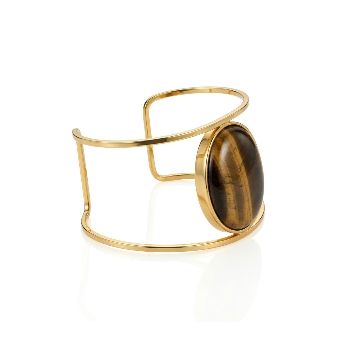 A wide, open 18K gold-plated bracelet with a bold oval Tiger’s Eye gemstone is displayed. The Stella Cuff from JAREDJAMIN Jewelry features clean lines, a polished finish, and modern sculptural design, shown on a white background.