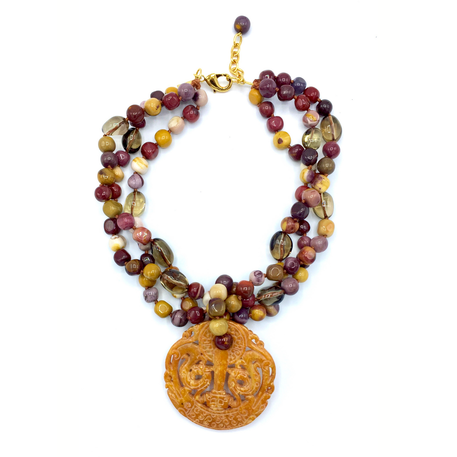 The Temple Pass Gemstone Pendant Necklace by JAREDJAMIN Jewelry Online features multistrand round Jasper beads in burgundy, brown, yellow, and beige with a large yellow-orange carved stone pendant and gold-toned clasp, shown on a white background.