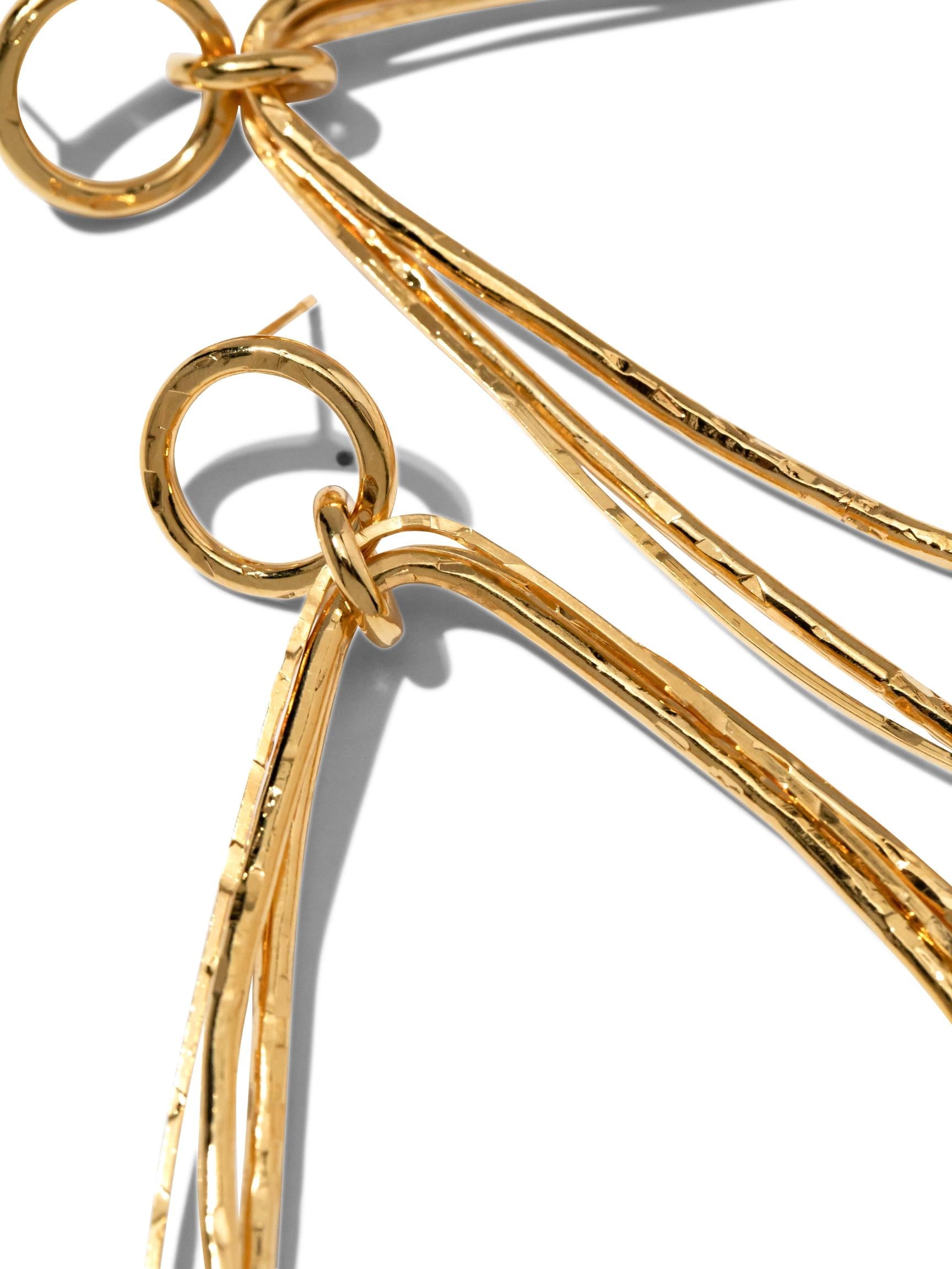 The Tereza Tear Dangle Post Earrings by JAREDJAMIN Jewelry Online feature a cascading silhouette with three interconnected, slender 18K gold-plated teardrop loops hanging from a small circular loop, offering an elegant and sophisticated look with their shiny, reflective surface.