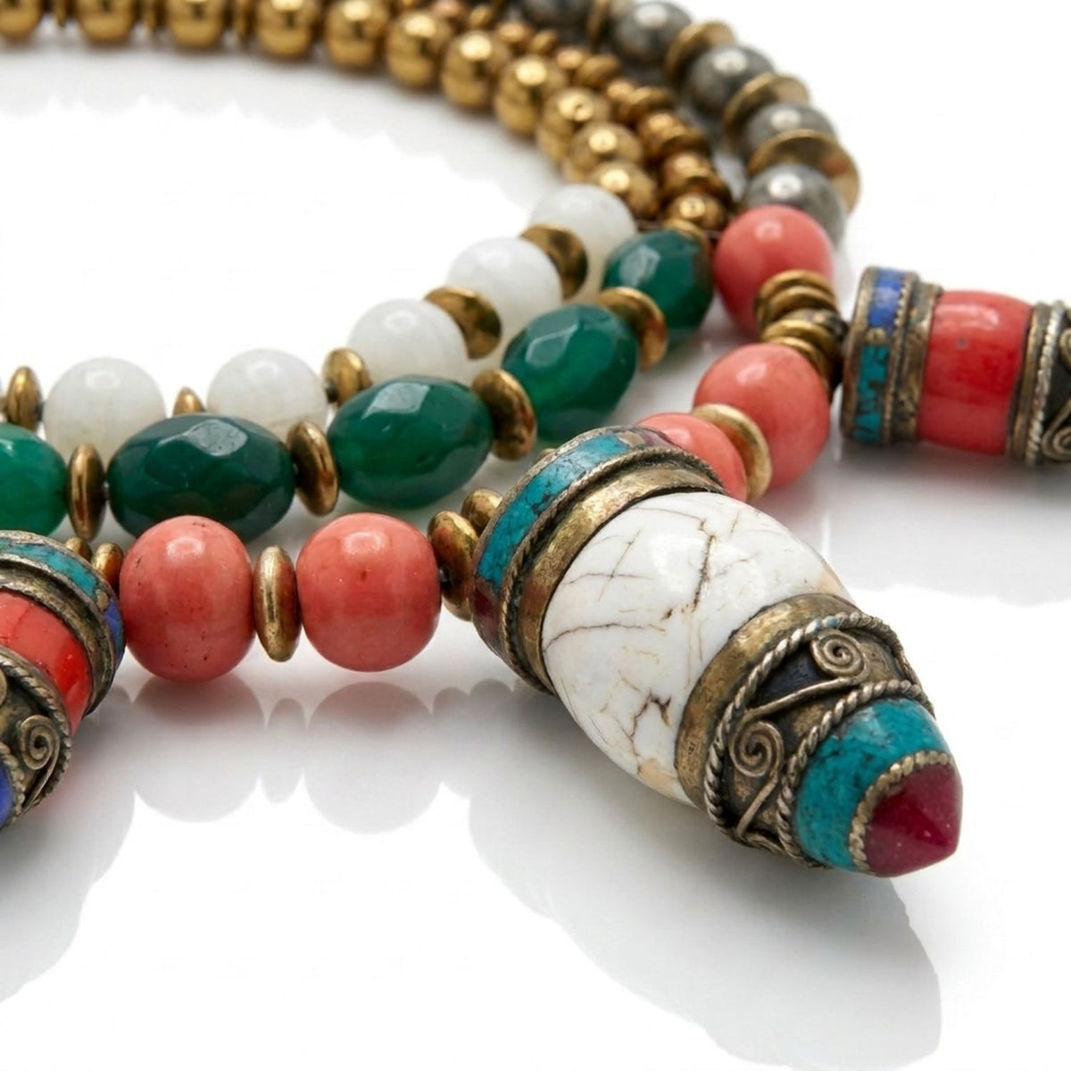 Macro studio detail shot focusing on the three hand-inlaid gemstone pendants, coral-colored mother-of-pearl beads, green faceted agate, and white stone components, displaying the antique patinated metalwork.