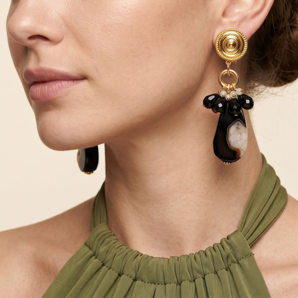 Side profile portrait of a model wearing the Veda black agate clip-on earrings paired with an olive green top, demonstrating their 3.5-inch vertical drop and comfortable lobe placement.