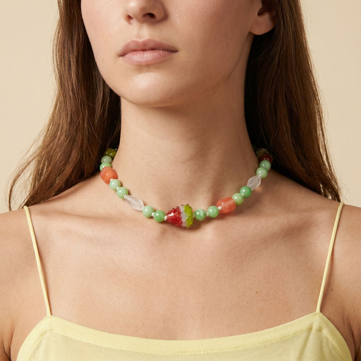 Close-up shot of a model wearing the converted 16-inch Watermelon Crush gemstone strand as a high-fashion choker necklace, showcasing its structural versatility, color composition, and coastal luxury aesthetic against a cream top.