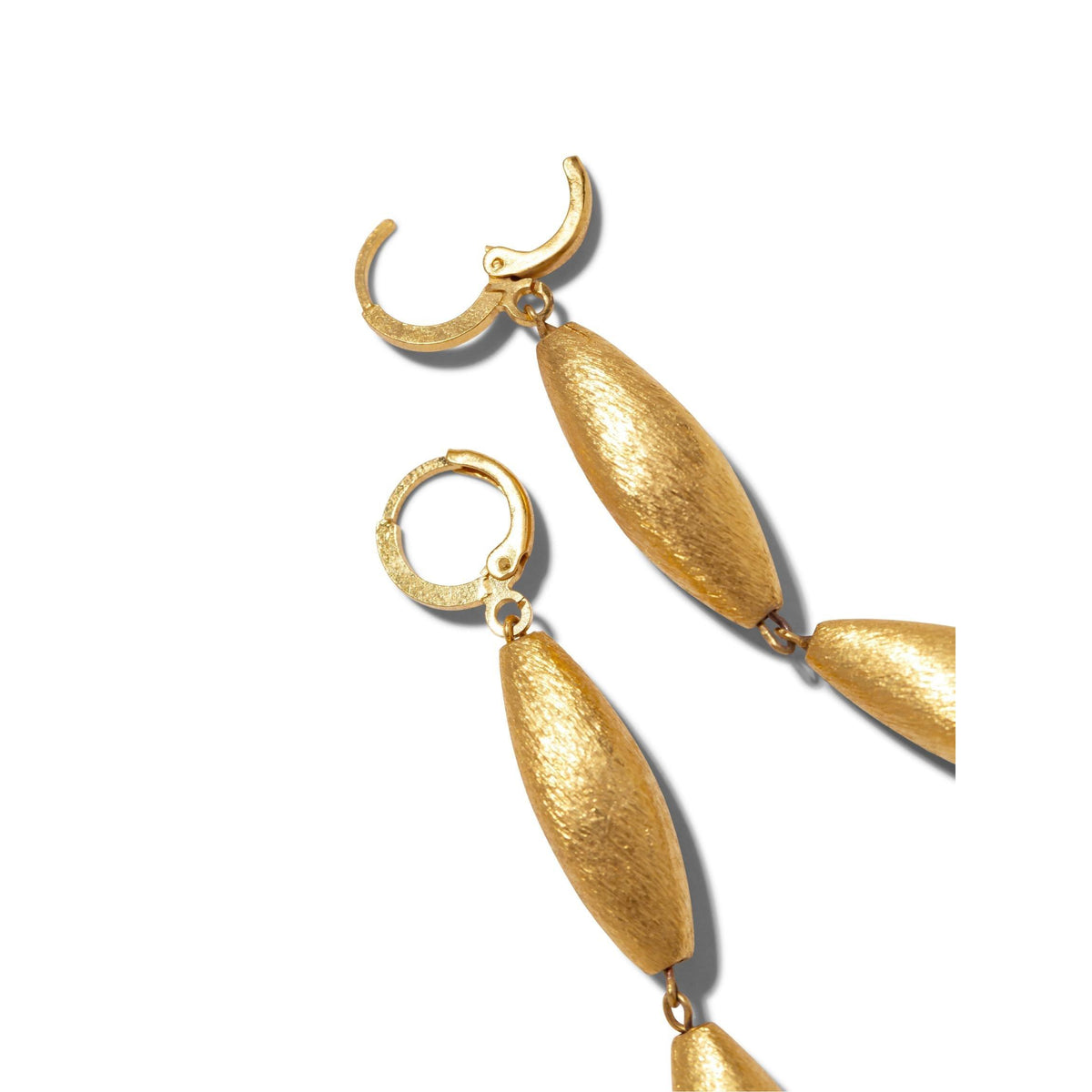 Un gros plan of JAREDJAMIN Bijoux en Ligne’s Zeppelin Cora 3 pendante or Leverback boucles d'oreilles avec texturé, mat-finish, elongated plaqué or beads et hinge clasps, arranged diagonally sur un fond blanc, partially out of frame.