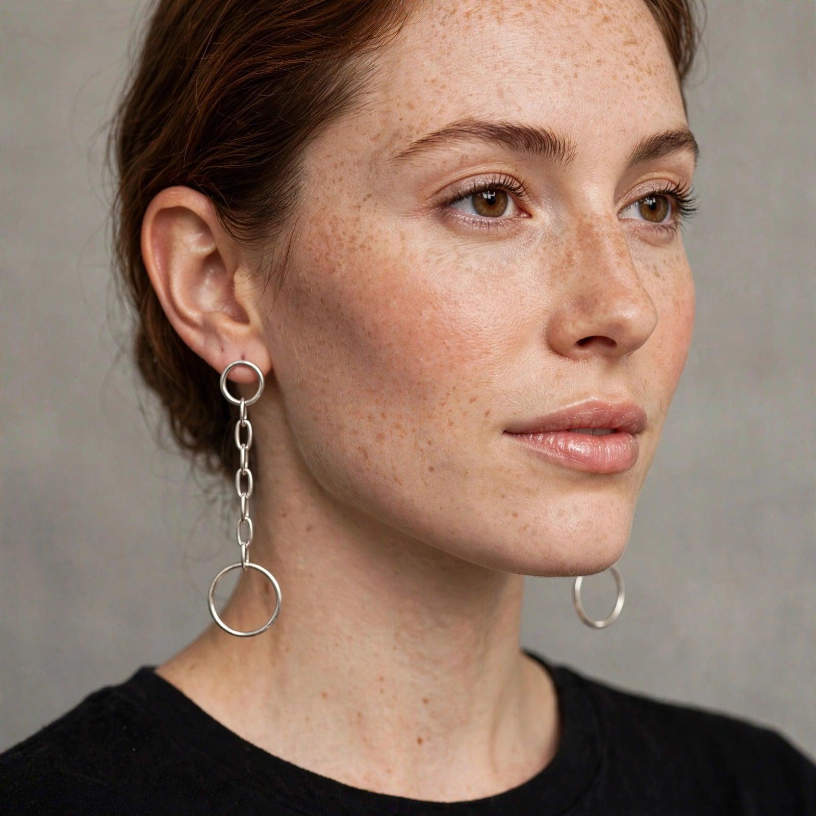 The Silver Chain Reaction Drop Post Earrings by JAREDJAMIN Jewelry Online feature a small hoop, short chain, and larger hoop in a minimalist, industrial design—creating a striking matching set shown on a white background.