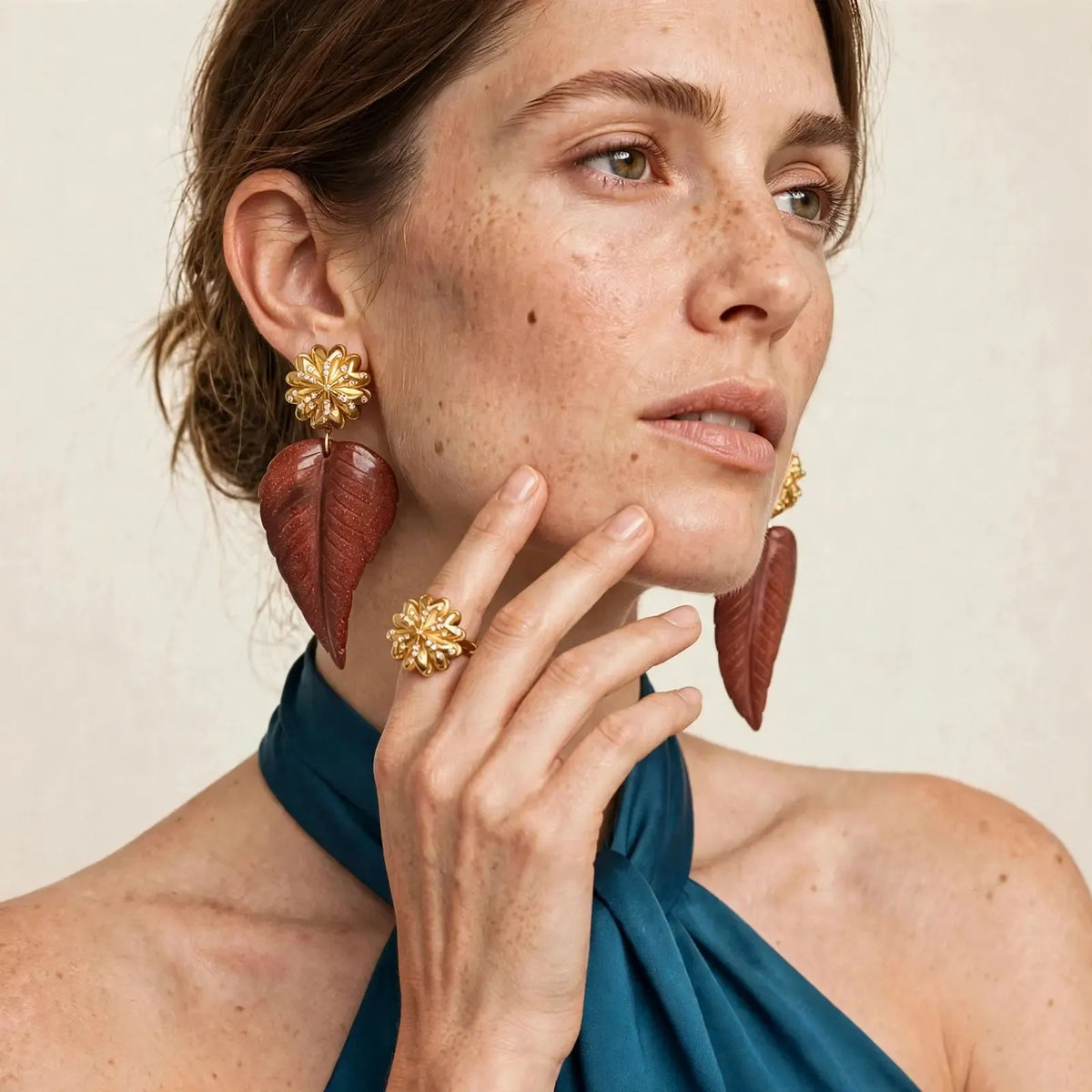 Model wearing the JAREDJAMIN Chrysanthemum Gold Plated Ring on her index finger, styled with the matching chrysanthemum clip-on earrings with gold sandstone leaf drops.