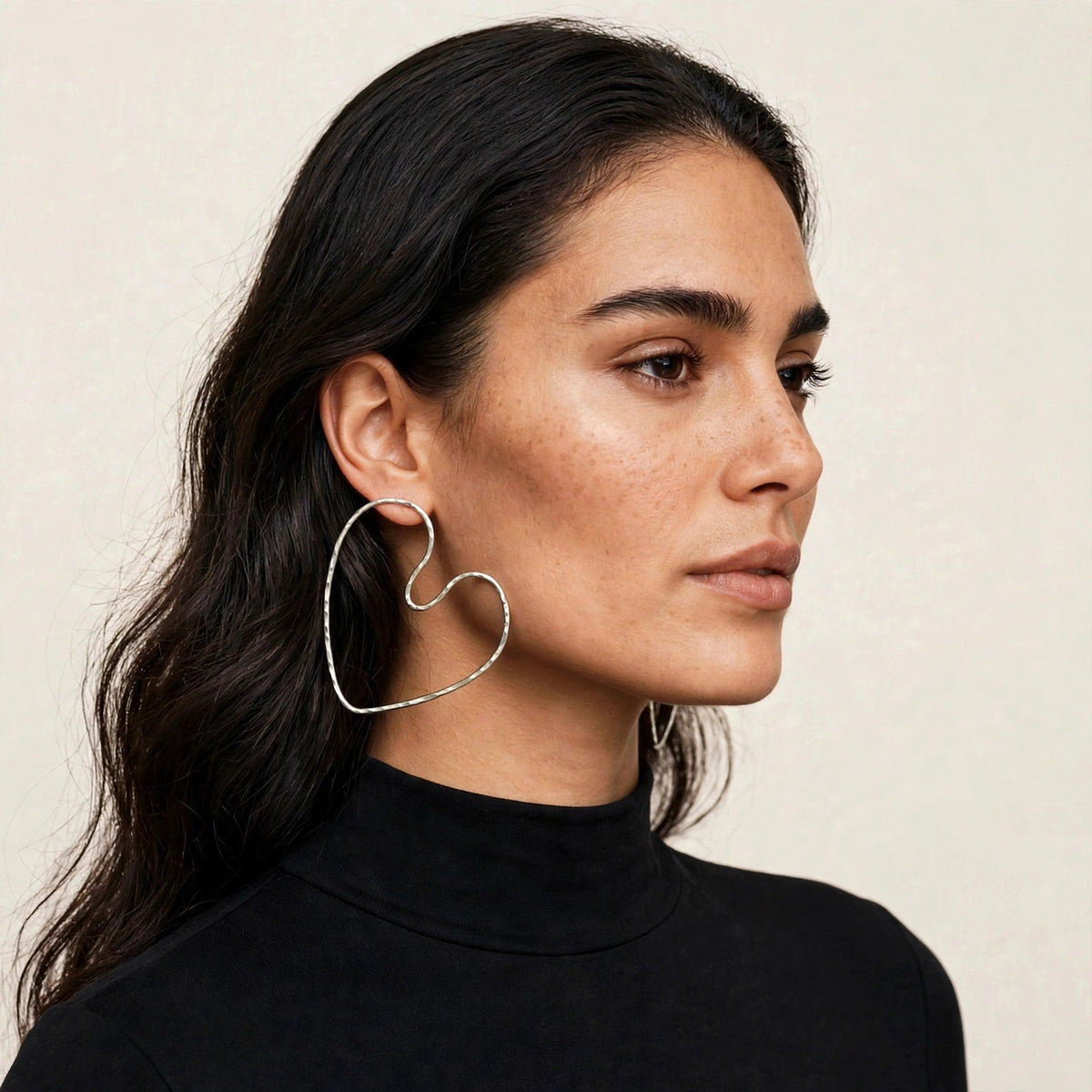 Silver Large Fluttering Heart, model wearing silver heart earrings, a large open hammered wire heart hoop, profile view.