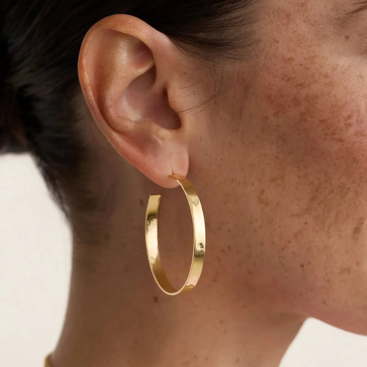 Heather Hoop Post Earrings worn on model — close-up of the flat 5.5mm gold ribbon hoop