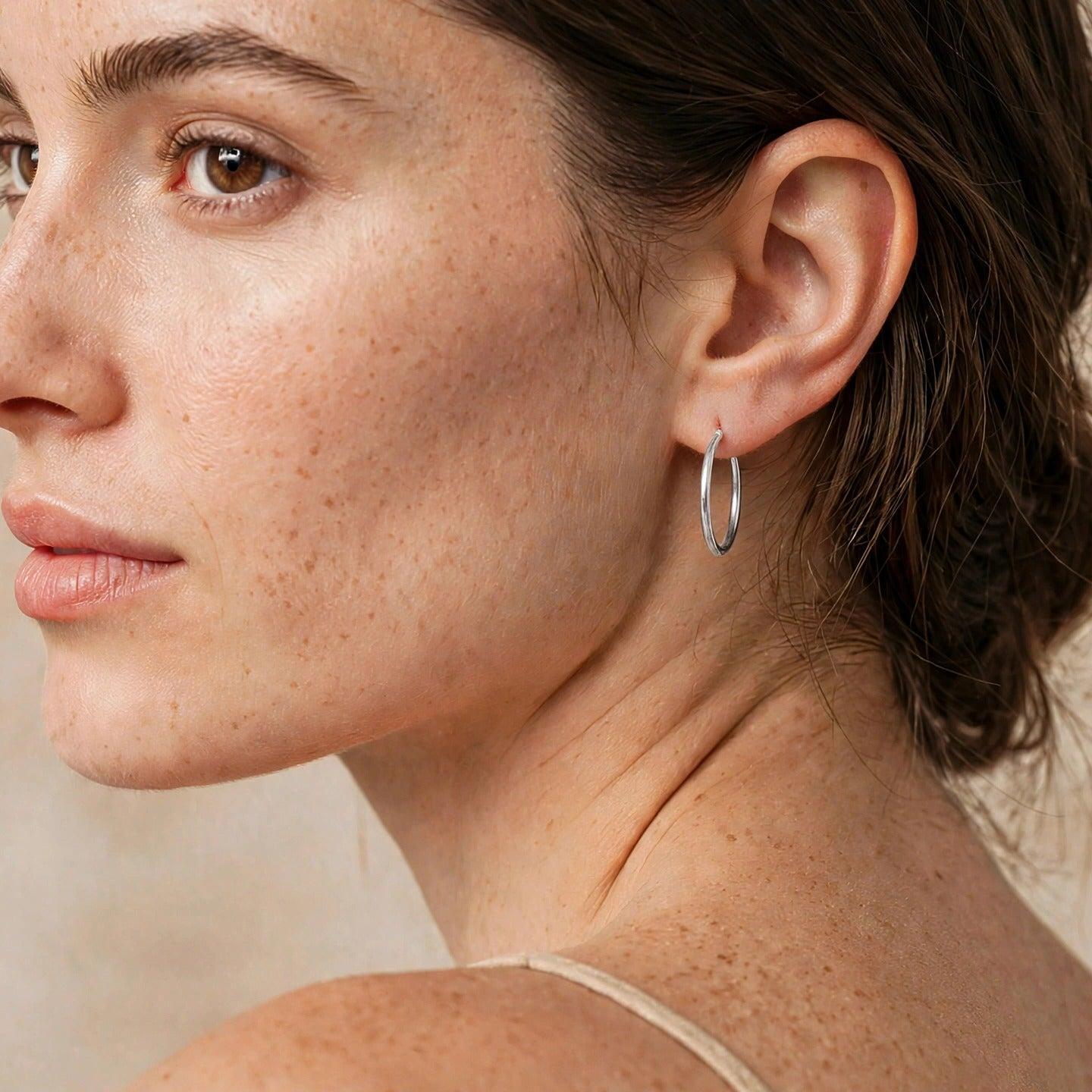 Two Silver Kahlo Hoop Click-Top Earrings xs by JAREDJAMIN Jewelry Online are shown on a white background—one earring lies flat with the latch closed, while the other highlights its click-top closure mechanism.