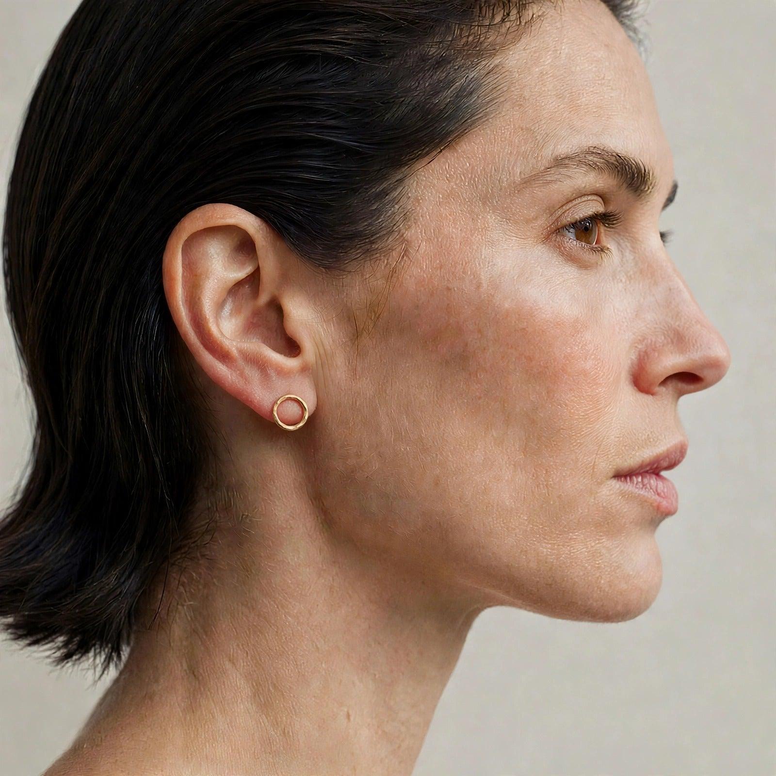 Small Rhodri Textured Circular Post Earrings in 18k gold plate — a pair of hand-hammered closed gold rings, 15.25 millimeters in diameter, on a white background.