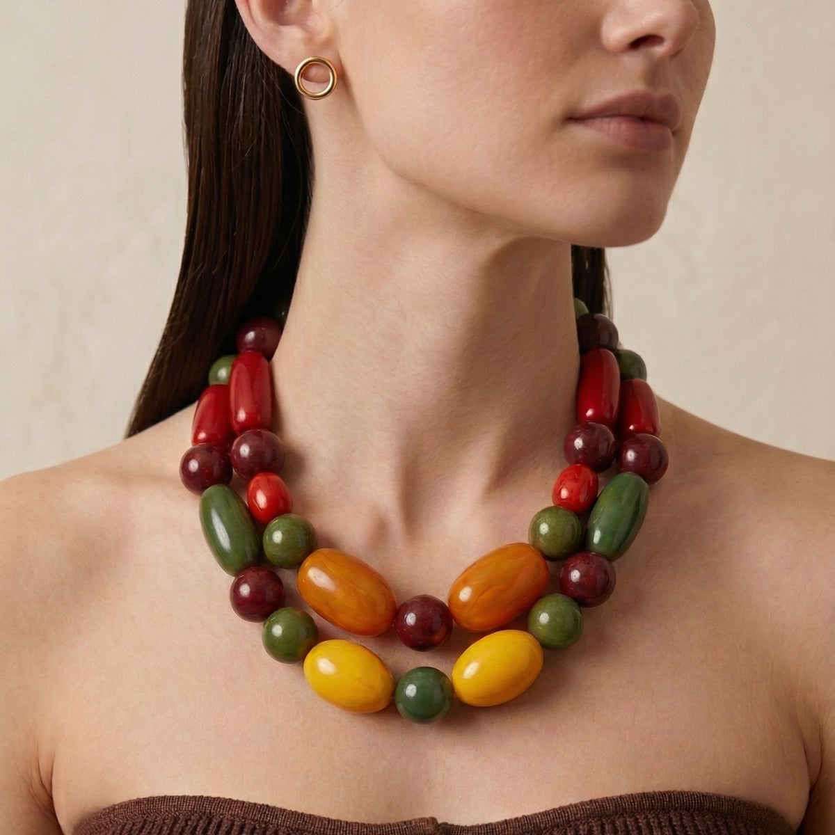 Los Tallulah llamativo Collar de JAREDJAMIN—large oval beads in yellow, green, red, y burgundy con a brushed finish—crafted in small batches in West Hollywood. Artisanal, sustainable de lujo; oro circle pendientes. Light beige background.