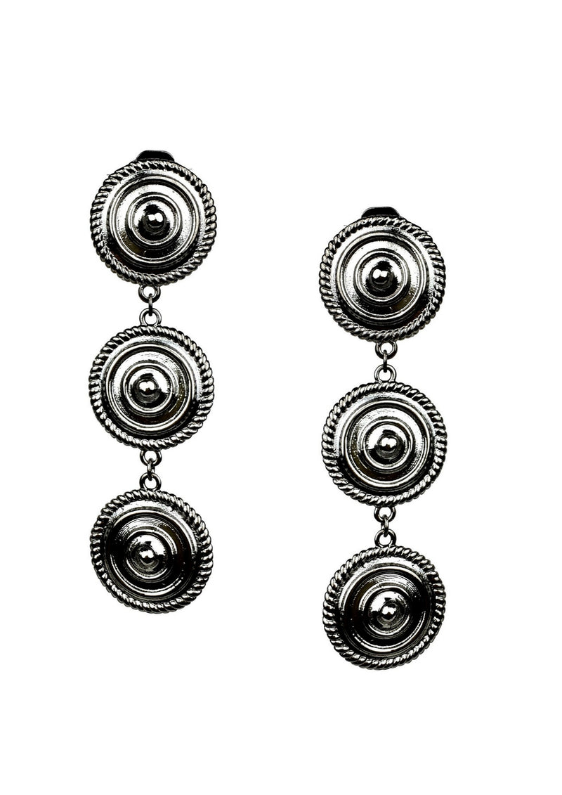 The Minerva Black Clip-on Earrings by JAREDJAMIN Jewelry are bold silver-tone pieces featuring two connected round concentric ridged discs bordered by beaded rope, showcasing a striking, vintage-inspired design.
