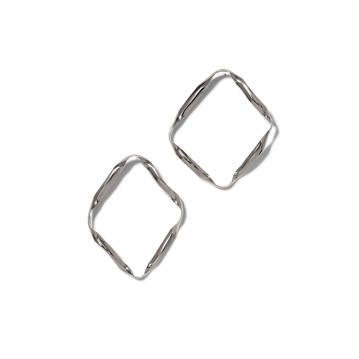 Les argent Ribbonelle boucles d'oreilles par JAREDJAMIN Bijoux en Ligne are argent plated, square-shaped créoles avec a unique twisted design, displayed diagonally sur un fond blanc avec soft gray shadows to the right.