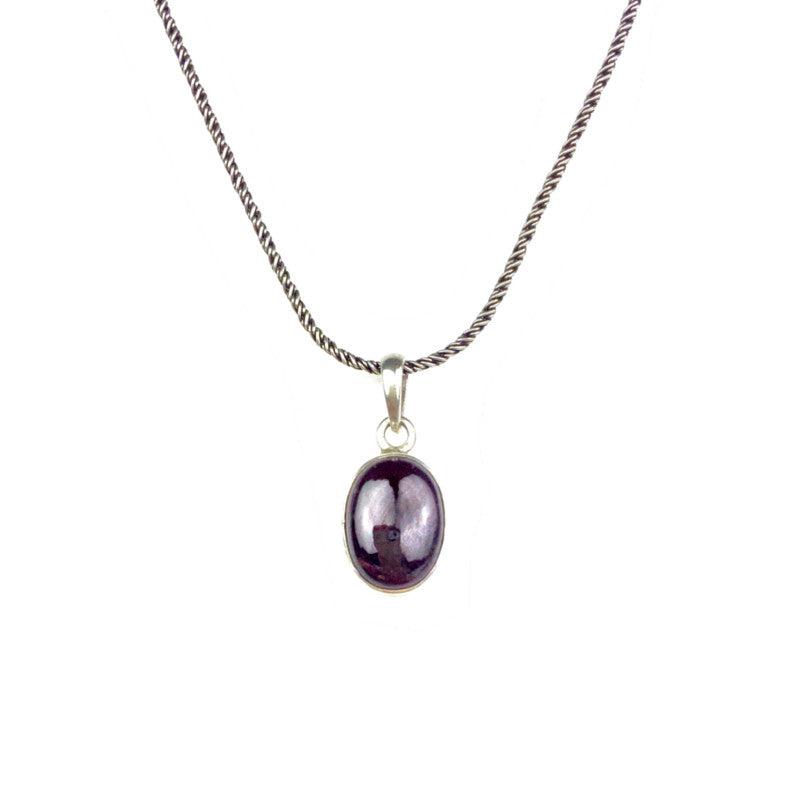 The Gage Garnet Necklace by JAREDJAMIN Jewelry Online is a sterling silver chain with a hook clasp, featuring an oval polished deep garnet pendant in a simple bezel, displayed against a white background.